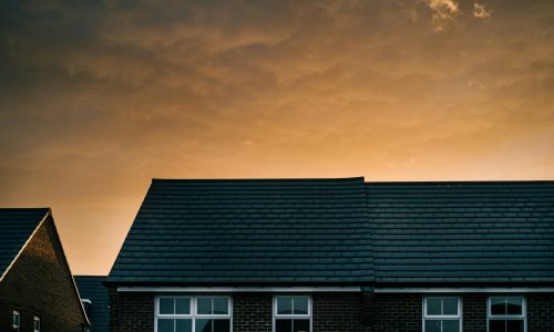 Roofline of modern houses against a dramatic sunset sky, symbolising home safety and electrical upgrades.